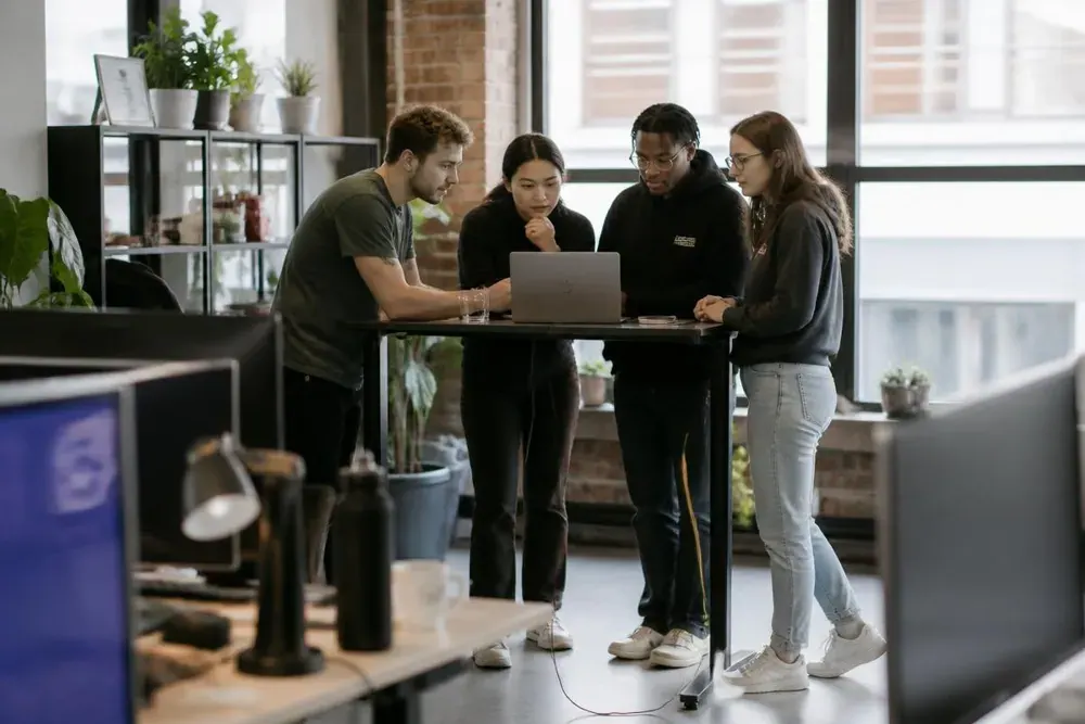 Junges Team im Loft-Büro betrachtet gemeinsam einen Laptop